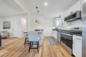 A modern kitchen with white cabinets, stainless steel appliances, and a dining area with a table and chairs.