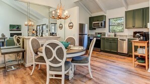 A modern kitchen with a dining area, featuring a chandelier, green cabinets, and a large window. - Cozy condo in Big Canoe! - Misty Ridge (Jasper)