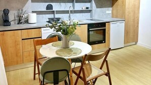 Una cuina moderna amb armaris de fusta, una illa central, i una zona de menjador amb dues cadires i una taula.