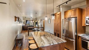 Una cocina moderna con armarios de madera, electrodomésticos de acero inoxidable y una isla de mármol con taburetes.
