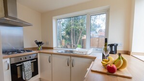 A modern kitchen with a gas stove, oven, and a window with a view of trees. - 3bed House in Stockton-on-tees- Free Wifi, Parking (Stockton-on-Tees)