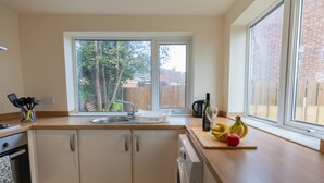 A kitchen with white cabinets, a wooden countertop, a sink, and a window with a view of trees and a fence. - 3bed House in Stockton-on-tees- Free Wifi, Parking (Stockton-on-Tees)