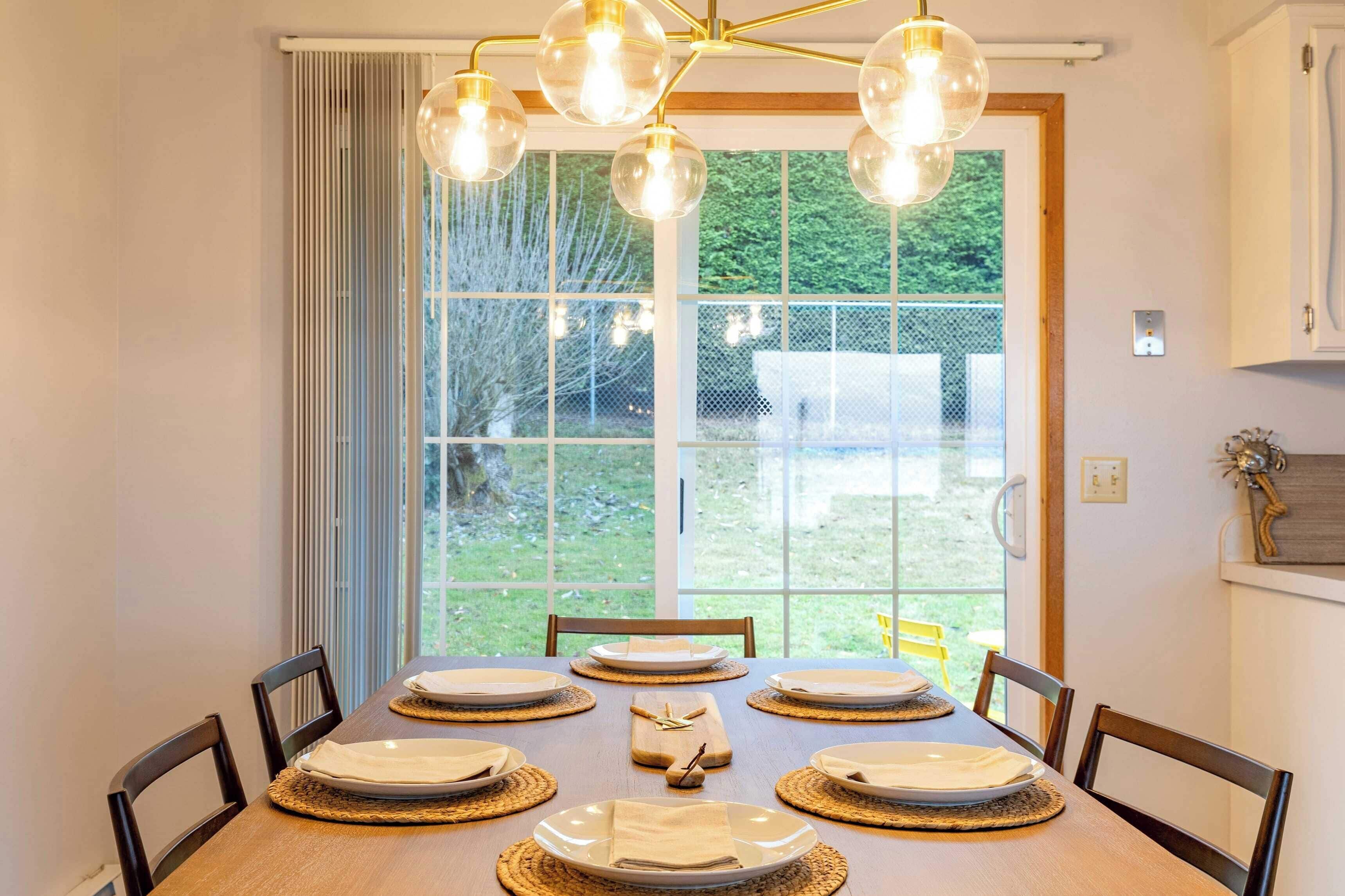 A dining area with a wooden table set for six, surrounded by chairs.