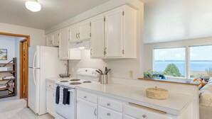 A modern kitchen with white cabinets, a stove, and a refrigerator.