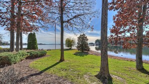 A park with a lake, trees, and a bench. - Bear Creek Lodge by Avantstay Lakefront + Dock (Mooresville)