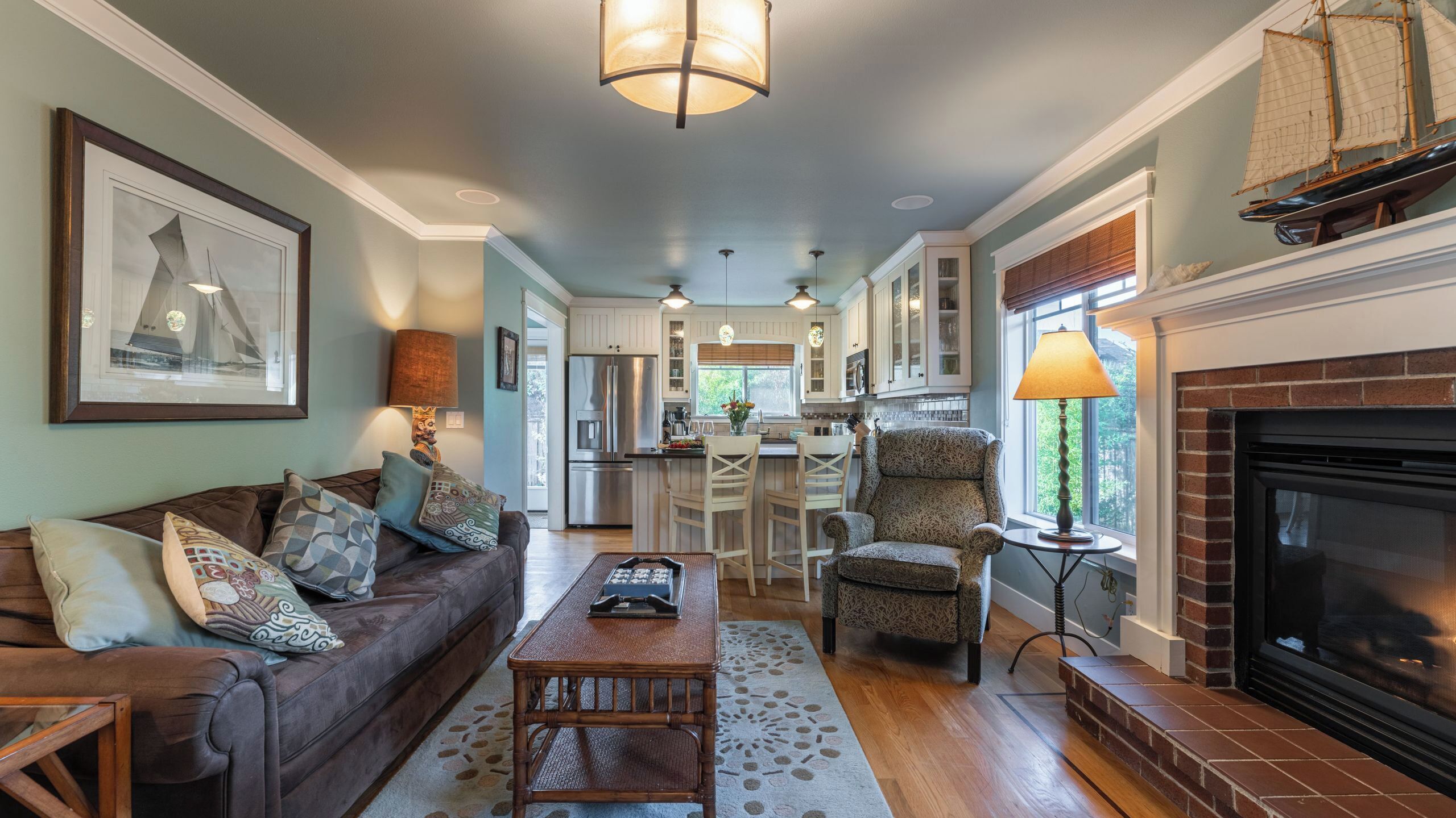 A spacious living room with a fireplace, a dining area with bar stools, and a kitchen with white cabinets.