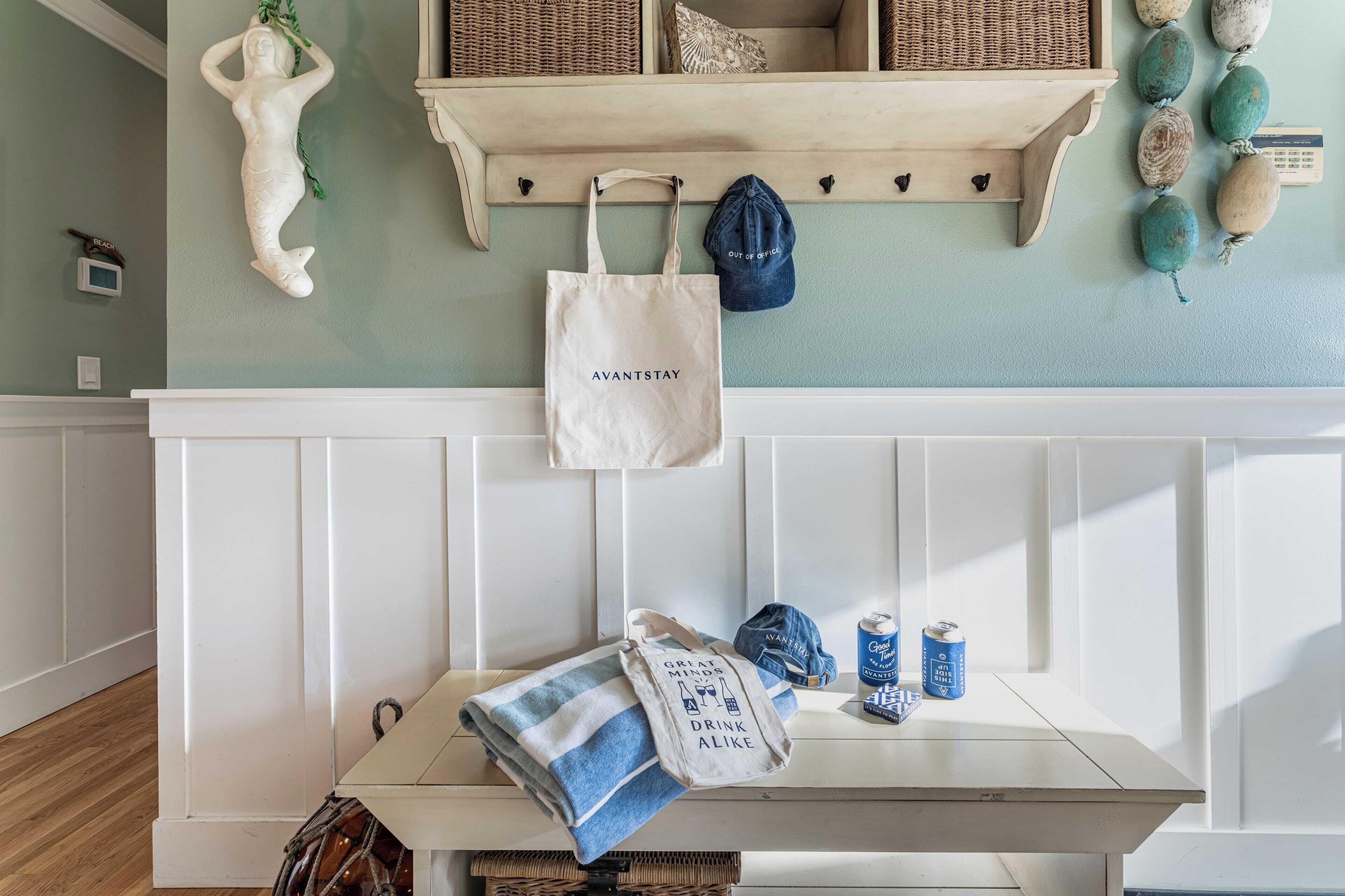 A room with a white bench, a wall-mounted shelf with decorative items, and a hanging bag.