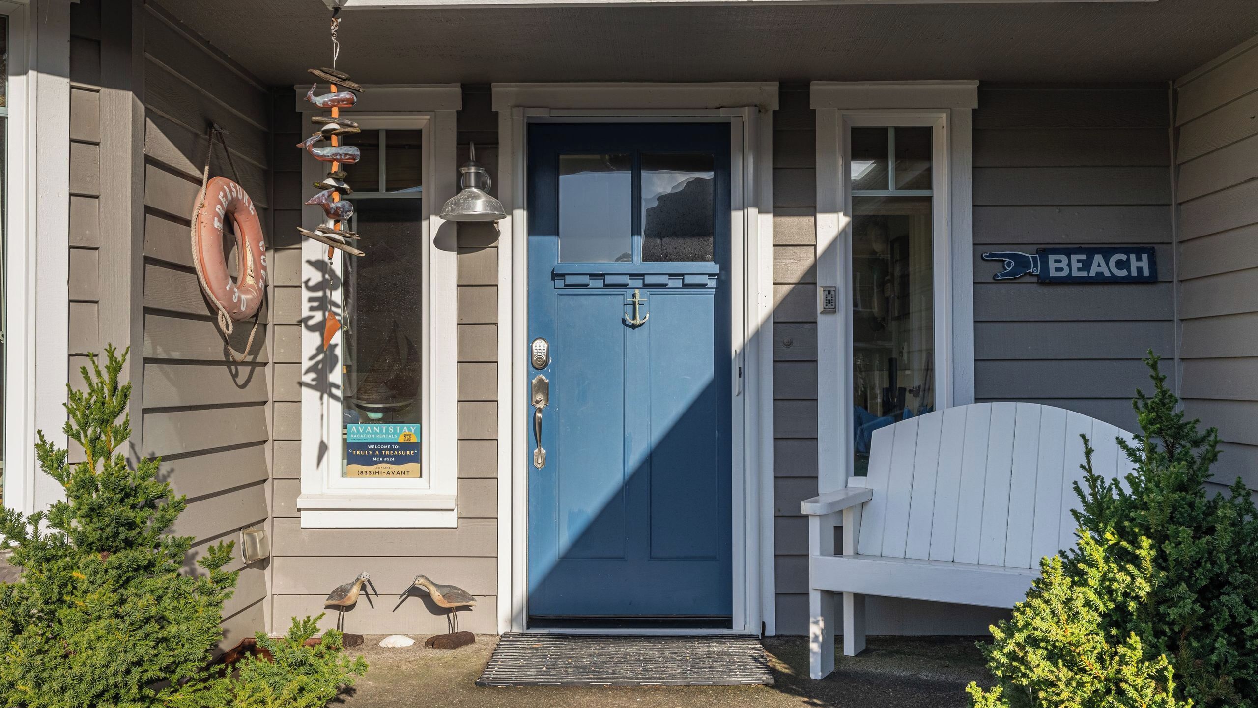 A blue door with a white bench and a sign reading 'BEACH' on the side of the building.