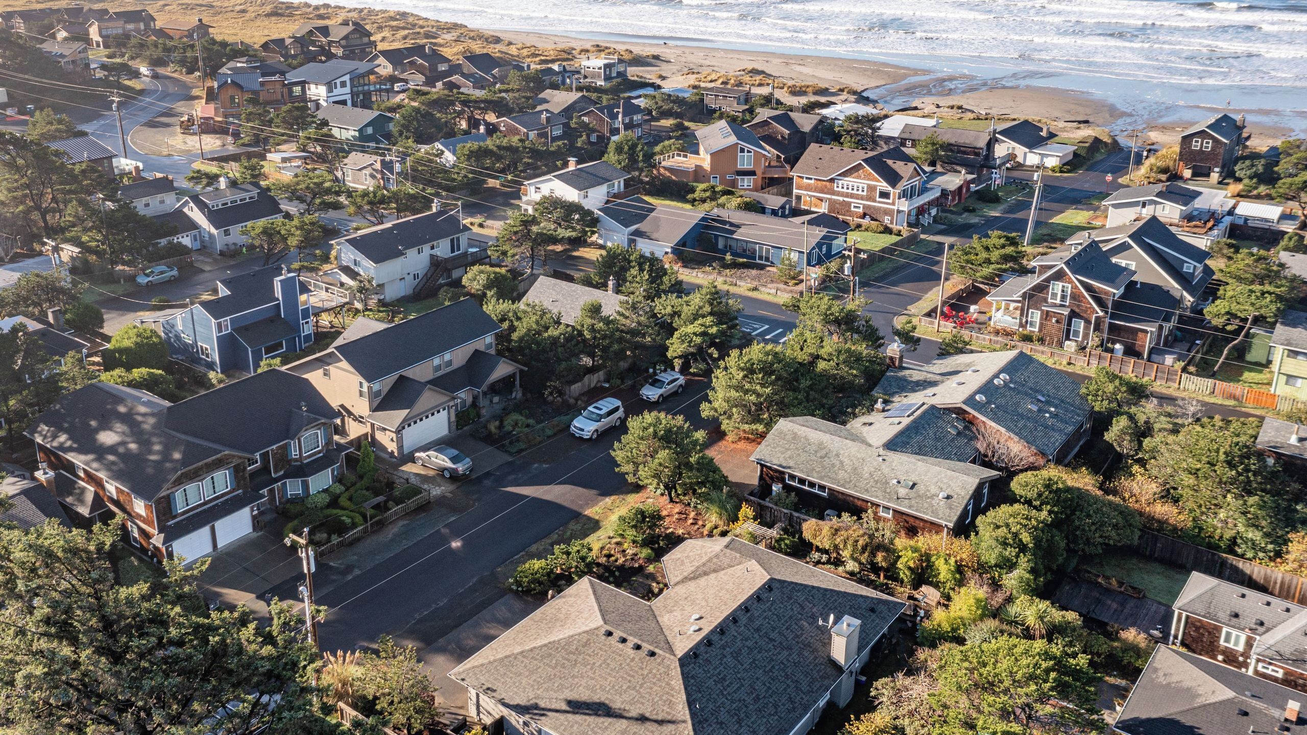 A residential area with houses, roads, and a beach in the background.