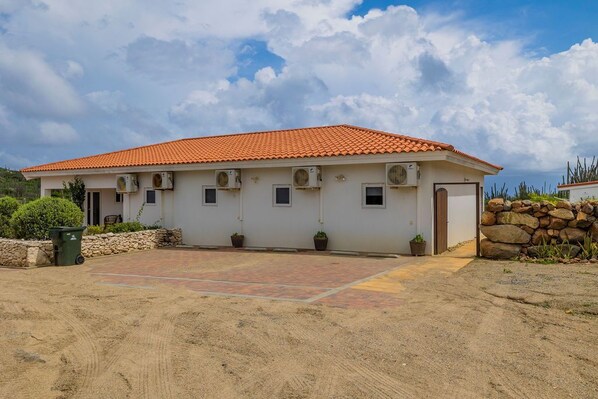 A single-story building with a red-tiled roof, multiple air conditioning units, and a paved driveway.