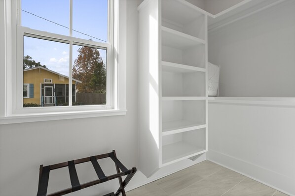 A room with a large window, built-in shelving, and a bench.