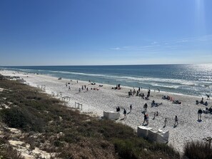 Een strand met mensen die wandelen en zitten, en een heldere lucht.