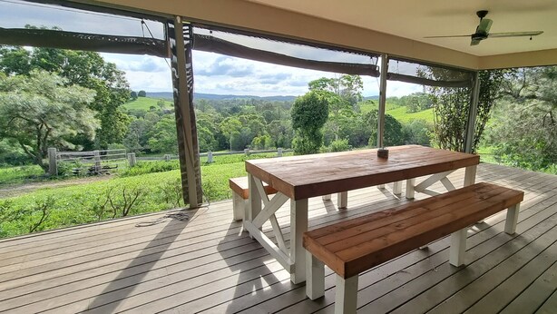 An outdoor wooden deck with a table and benches, overlooking a lush green landscape.