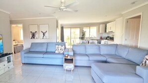 A modern living room with a flat-screen TV, a grey sectional sofa, and a small side table.