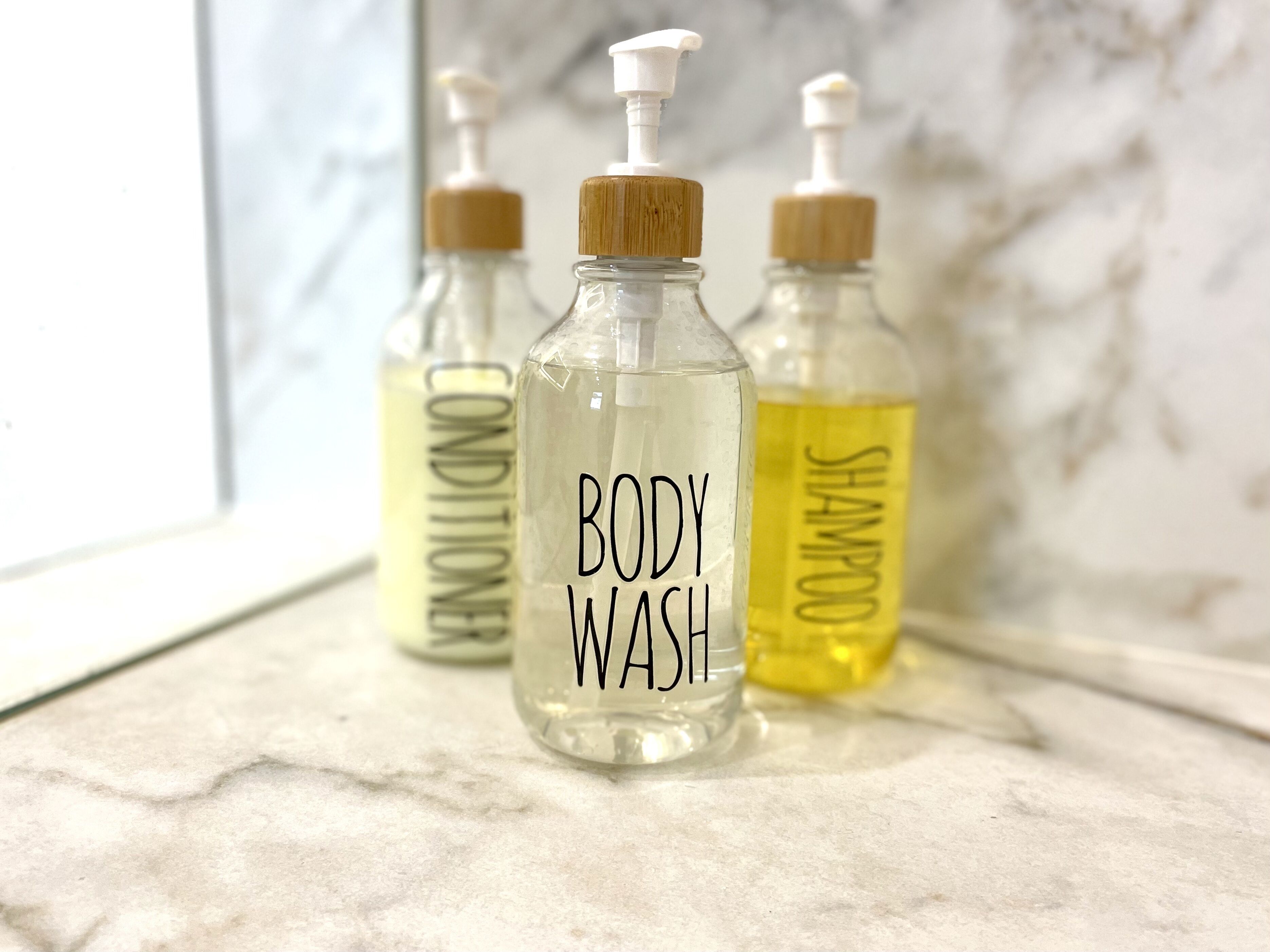 Trois bouteilles de gel douche sur une surface en marbre.