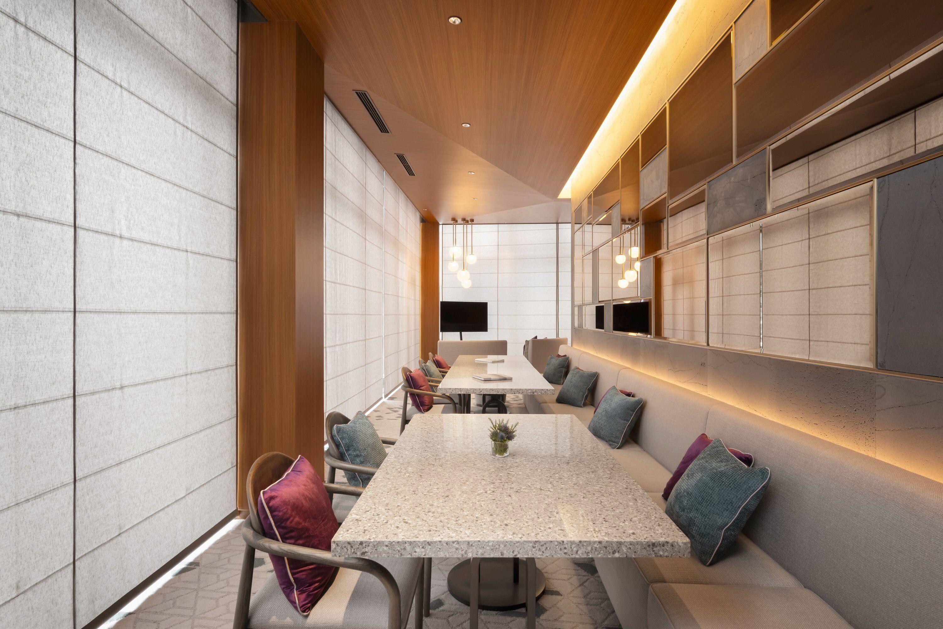 A modern conference room with a long table, comfortable seating, and a large screen.