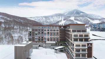A modern multi-story hotel with a central courtyard, surrounded by snow-covered mountains.
