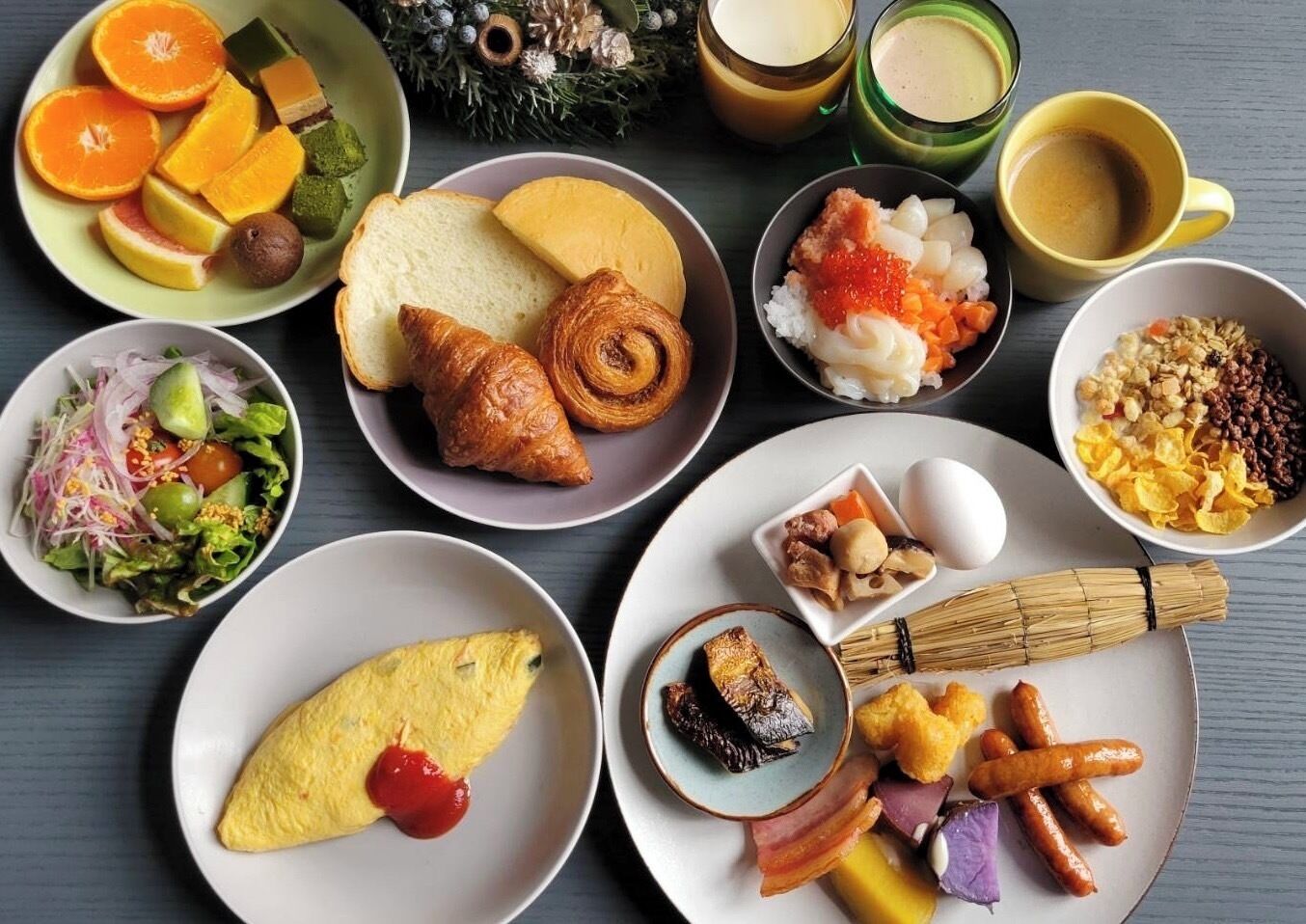 A variety of dishes including sushi, croissants, and an omelette, arranged on multiple plates.