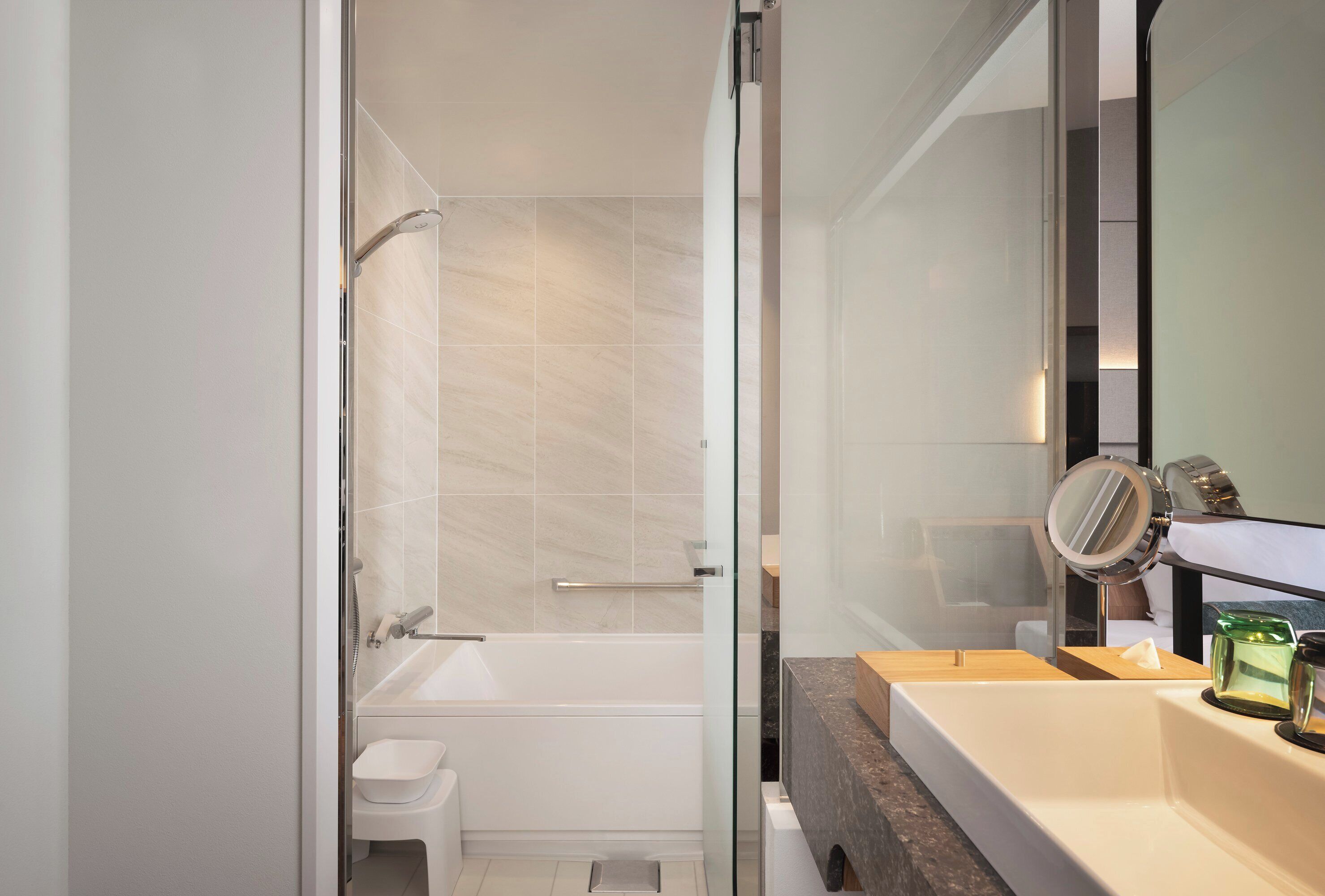 A modern bathroom with a glass shower enclosure, a bathtub, a toilet, and a vanity with a mirror.