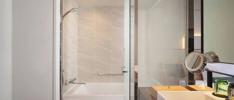 A modern bathroom with a glass shower enclosure, a bathtub, a toilet, and a vanity with a mirror.