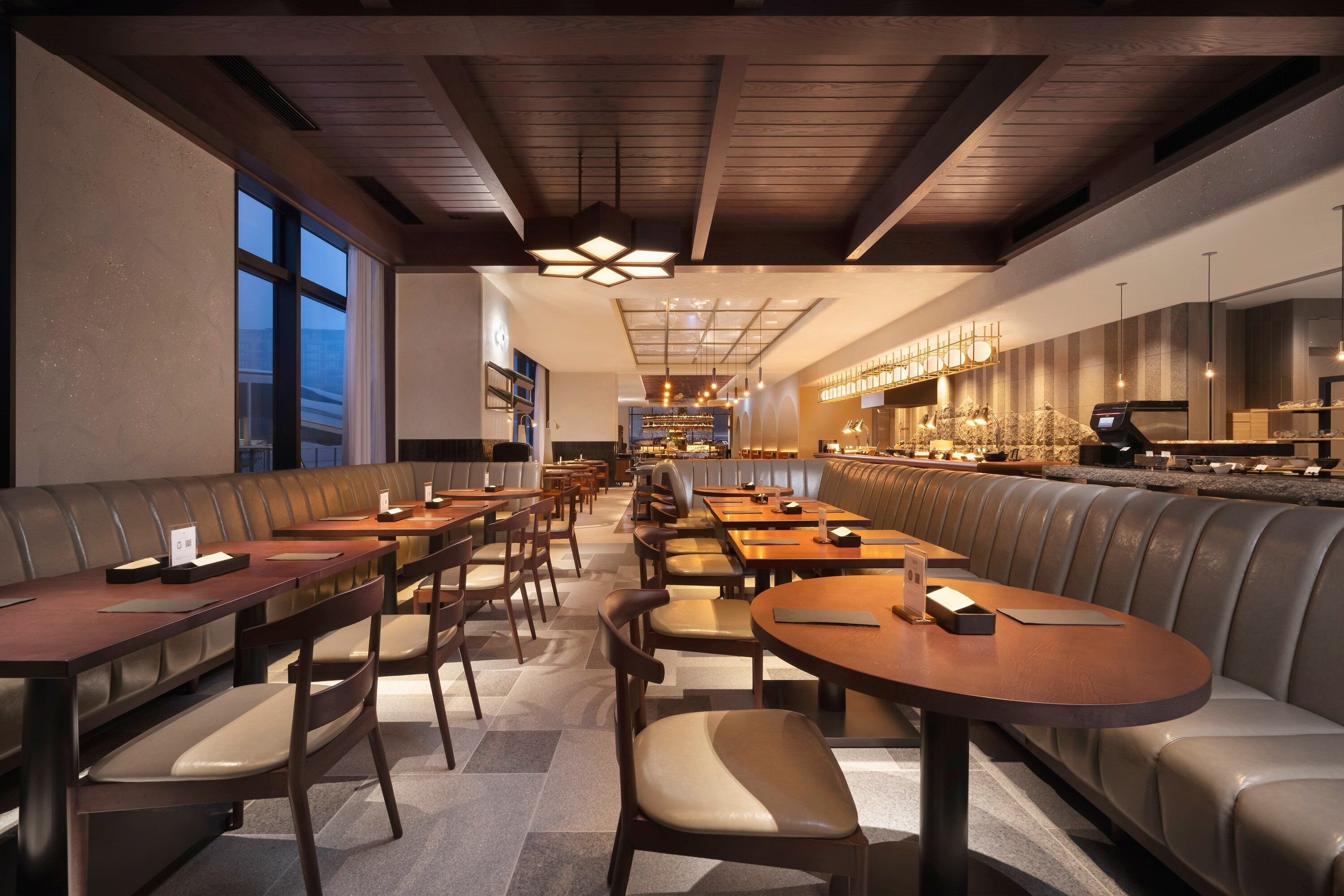 A restaurant with booths and tables, a bar area, and a view of the city.