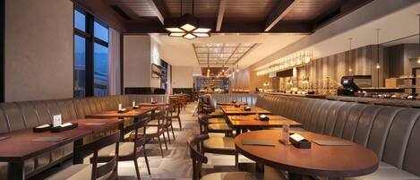 A restaurant with booths and tables, a bar area, and a view of the city.