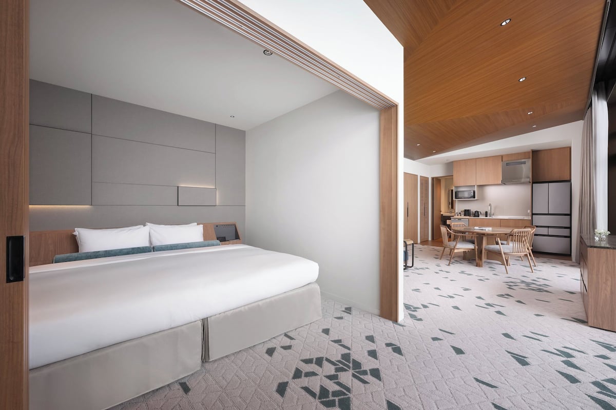Ein modernes Hotelzimmer mit einem großen Bett, einer Küchenzeile und einem Essbereich.