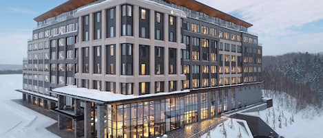 A modern multi-story hotel with a glass facade, large windows, and a flat roof.