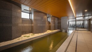Un área de piscina interior moderna con paredes de piedra, suelo de baldosas y techo de madera.