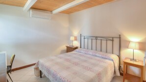 Un dormitori amb un llit, dues taules de nit, un escriptori i una cadira.