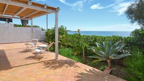 Un pati cobert amb dues gandules, un paviment de rajoles i vista al mar.