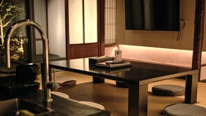 A modern kitchen with a black countertop, a built-in sink, and a flat-screen TV mounted on the wall. - Tsumugi Kamiurokogatacho (Kyoto)