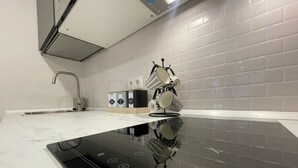 Une cuisine moderne dotée d’une plaque de cuisson à induction noire, d’un robinet en acier inoxydable et d’un dosseret carrelé.