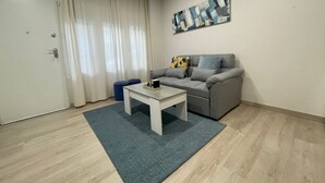 Un salon moderne avec un canapé gris, une table basse blanche et un tapis bleu.