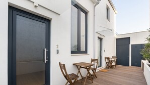 A modern exterior with a large sliding door, a small patio with wooden furniture, and a number '2' sign. - GuestReady - King's Retreat (Porto)