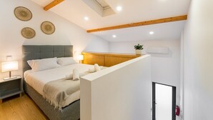 A bedroom with a bed, bedside tables, a nightstand, a wooden ceiling, and a small plant. - GuestReady - King's Retreat (Porto)
