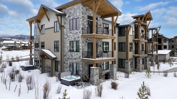 A multi-story hotel with a stone facade, wooden balconies, and a hot tub in the snow. - Elk Creek D102 private hot tub - 4 beds, sleeps 7 (Fraser)
