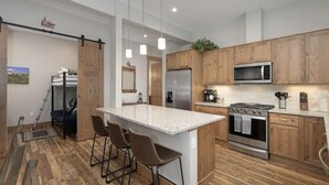 A modern kitchen with wooden cabinets, stainless steel appliances, and a central island with bar stools. - Elk Creek D102 private hot tub - 4 beds, sleeps 7 (Fraser)