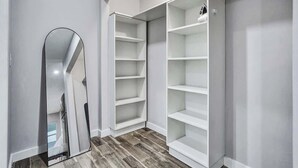 Ein begehbarer Kleiderschrank mit offenen Regalen und einem großen Spiegel.