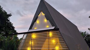 Un edificio moderno de forma triangular con fachada de vidrio e iluminación interior cálida.
