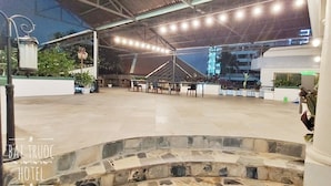An outdoor seating area with tables and chairs, a stone fountain, and potted plants. - Front Beach Hotel  (Ho Chi Minh City)
