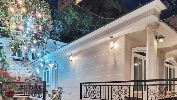 A stone staircase leading to a white building with a black railing, surrounded by potted plants and decorative lights. - Front Beach Hotel  (Ho Chi Minh City)