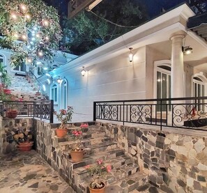 A stone staircase leading to a white building with a black railing, surrounded by potted plants and decorative lights. - Front Beach Hotel  (Ho Chi Minh City)
