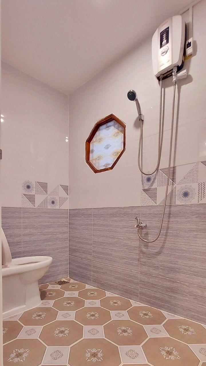 A bathroom with a shower, a toilet, and a wall-mounted heater.
