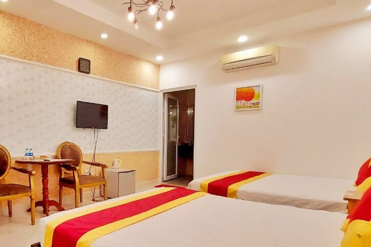 Ein Hotelzimmer mit zwei Betten, einem Schreibtisch mit Stühlen, einem Fernseher und einem Kleiderschrank.