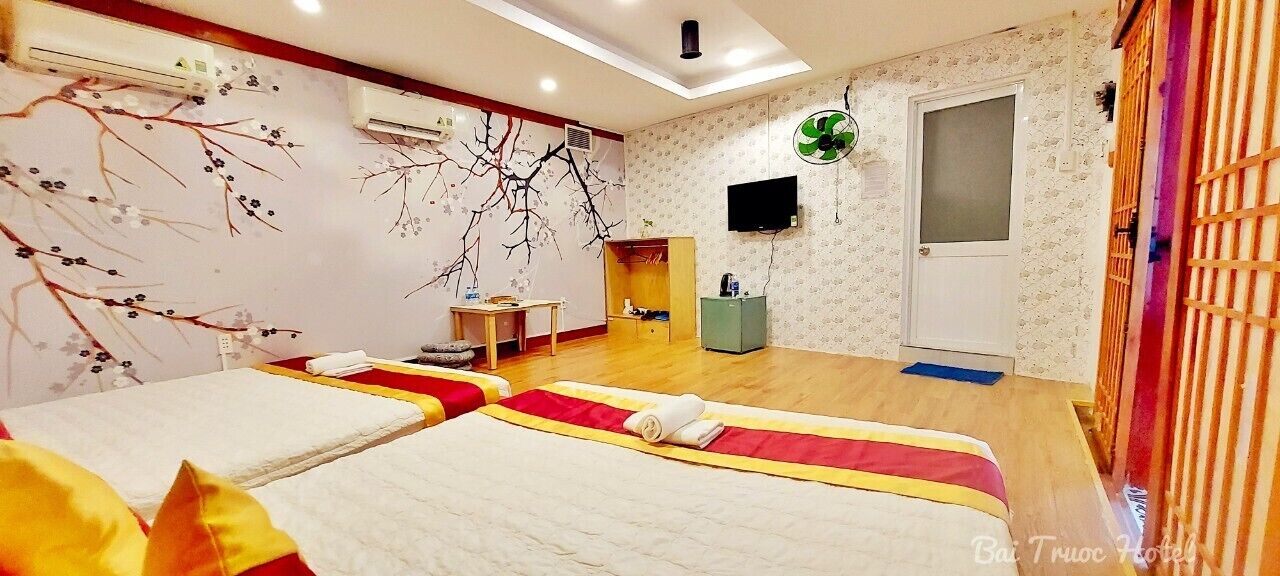 A hotel room with two beds, a TV, a wardrobe, and a small table.