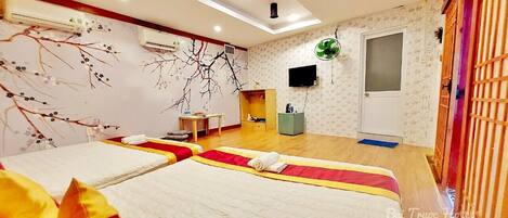 A hotel room with two beds, a TV, a wardrobe, and a small table.