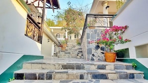 A narrow staircase with stone steps leading to a building entrance, surrounded by white walls and a green base. - Front Beach Hotel  (Ho Chi Minh City)