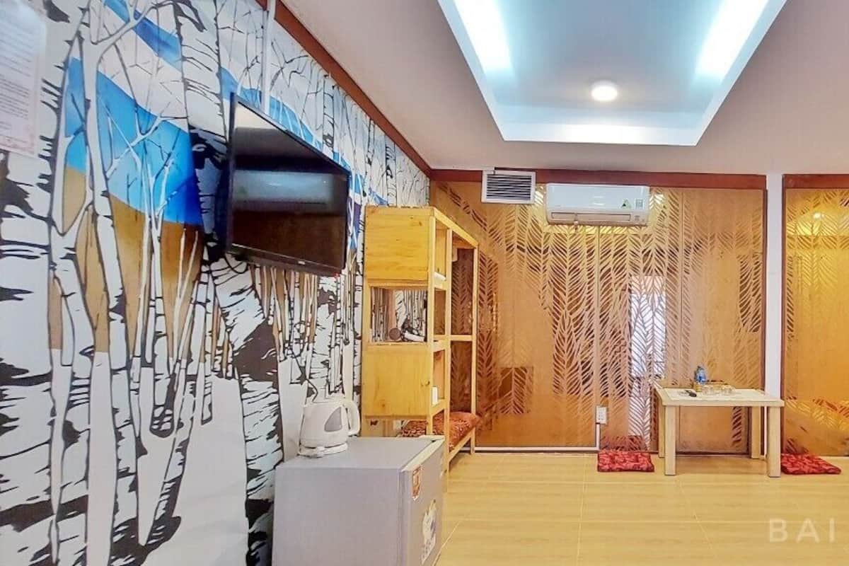 Ein Hotelzimmer mit Fernseher, einem kleinen Tisch, einer Couch und einer Wand mit Blattmuster.