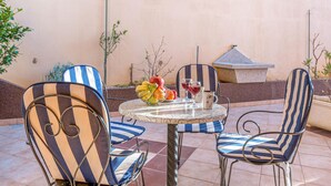 A patio with striped chairs and a table, a fruit bowl, and two glasses of red wine. - Lovely apartment in Baska Voda with swimming pool (Baska Voda)